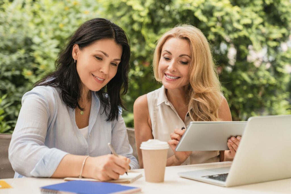 Two caucasian mature businesswomen best friends colleagues working together